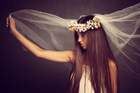 young beautiful woman with veil and wreath of flowers, profile, studio shotの写真素材