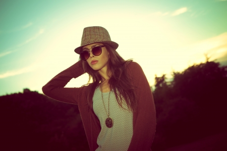 young hipster woman with hat and sunglasses outdoor shot at sunset retro colorsの写真素材