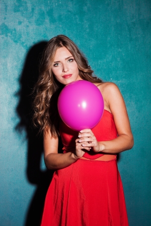 girl in red dress and balloon studio shot blue backgroundの写真素材