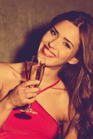 smiling  woman in red dress hold a glass of champagne  retro colorsの写真素材