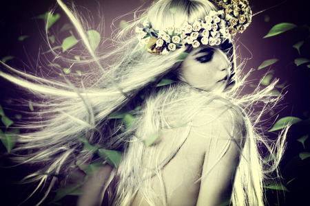 spring nymph with long blond hair in motion and wreath of flowers and leaves around composite photoの写真素材