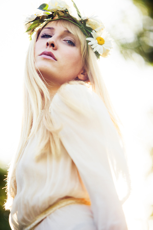 blonde beautiful young woman summer portrait with wreath of flowers in hair outdoor shotの写真素材