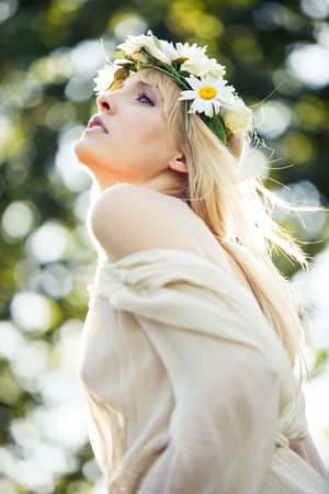 blonde beautiful young woman summer portrait with wreath of flowers in hair outdoor shotの写真素材