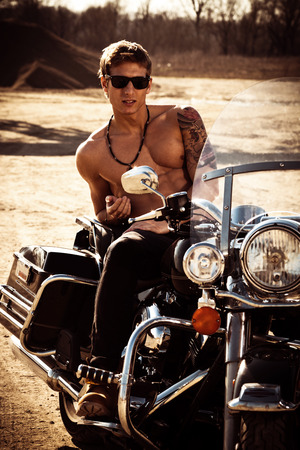 handsome muscular young man on a motorcycle summer day at sunsetの写真素材