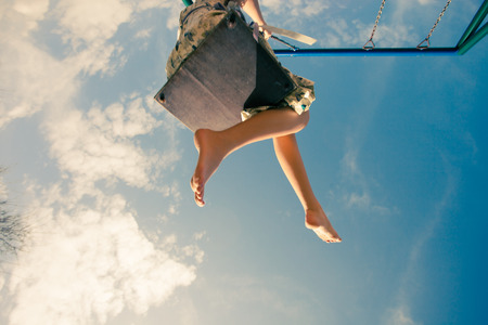 barefoot young woman in dress on swing outdoor in park warm spring dayの写真素材