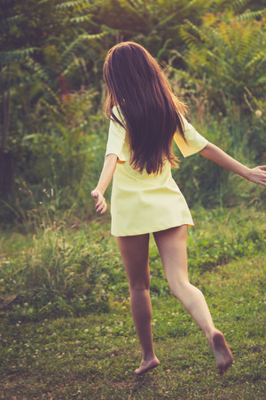 barefoot young woman in short dress  run in nature summer day at sunsetの写真素材