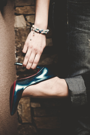 woman in jeans  hold shoe with one hand indoor shot closeupの写真素材