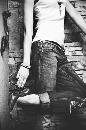 woman in jeans and T-shirt hold shoe with one hand indoor shot black and whiteの写真素材