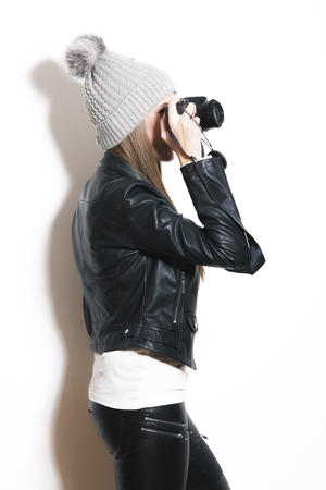 girl take photo with digital camera, wearing wool cap, leather jacket and black leggingsの写真素材