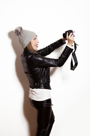 girl take selfie with digital camera, wearing wool cap, leather jacket and black leggingsの写真素材