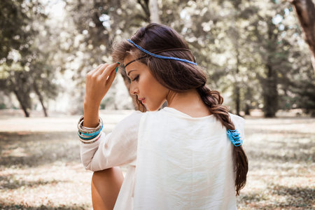 young beautiful woman portrait  in white dress and blue beads in hair, profile, outdoor summer day in forestの写真素材