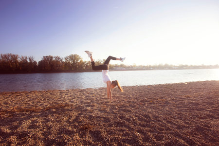 girl exercise by the lake sunny autumn day, full body shot, handstand