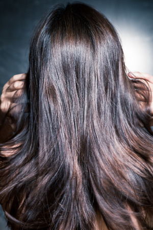 beautiful dark shiny long woman hair in motion, back view, studio shotの写真素材