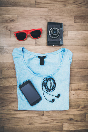 girl accessories background, t-shirt, smart phone, earphones, sunglasses, old camera on parquet from aboveの写真素材