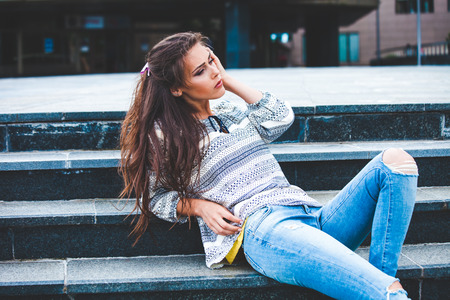urban girl portrait on stairs in blue jeans and shirtの写真素材
