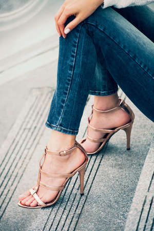 young woman sit on stairs in high heel golden sandals outdoor shot in the cityの写真素材