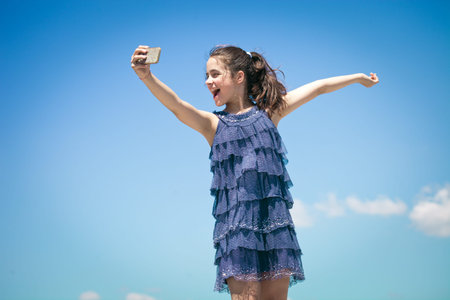 cute smiling girl make selfie against blue skyの写真素材