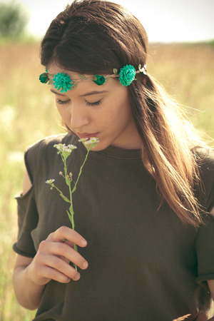 young woman in summer meadow hold chamomile flowerの写真素材