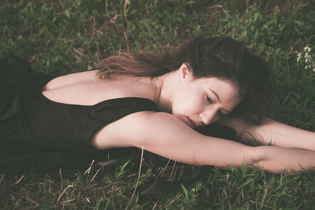 young beautiful woman in black dress lie in grassの写真素材