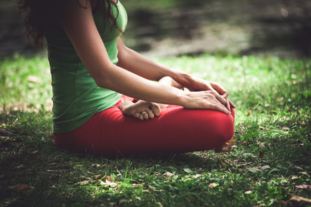 young woman in lotus position closeup in park summer dayの写真素材
