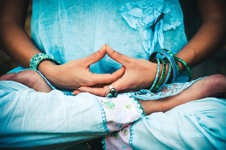 closeup of woman hands and legs in meditative pose practice yoga outdoor shot