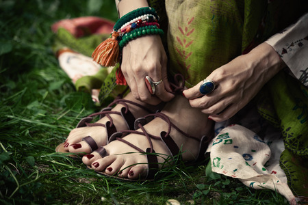 woman feet in boho style strap flat sandals on grass closeupの写真素材