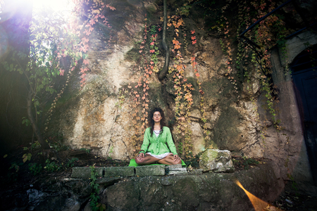 young woman practice yoga outdoor in front old rock wall with autumn leavesの写真素材
