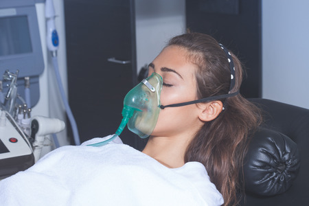 young woman with oxygen mask at hospital or cosmetics salonの写真素材