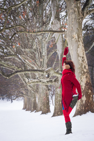 smiling young woman doing yoga in winter snow covered parkの写真素材