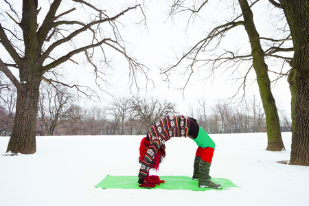 fit  young woman doing yoga in winter snow covered parkの写真素材