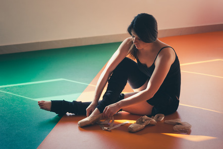 young woman dancer putting on ballet shoes prepare for training indoor shotの写真素材