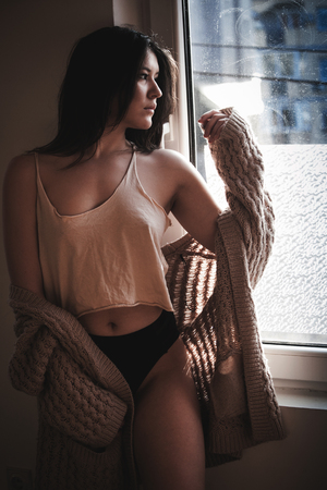 beautiful sensual young woman by the window portraitの写真素材