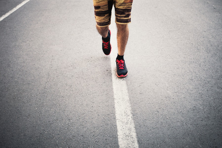 closeup of young man running over the street line summer day healthy lifestyle conceptの写真素材
