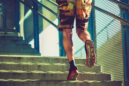 young man running up the stairs close up, sunny summer day outdoors in the city healthy lifestyle...