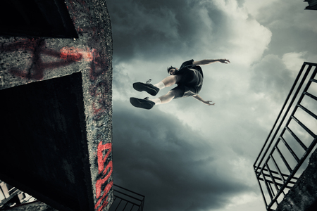 young man doing parkour jump in the city shot 
from belowの写真素材