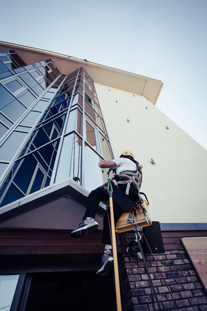 window washer working  at building outdoor hanging on ropeの写真素材