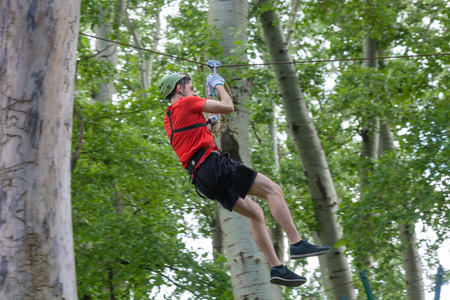 young man on zipline in adventure park in forestの写真素材