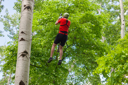 young man on zipline in adventure park in forestの写真素材