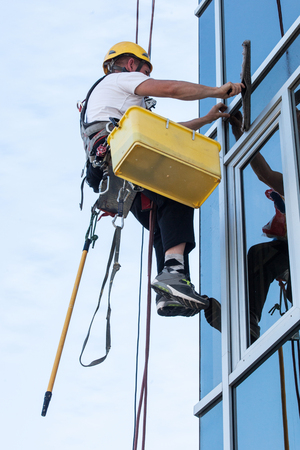 window washer working  at building outdoor hanging on ropeの写真素材