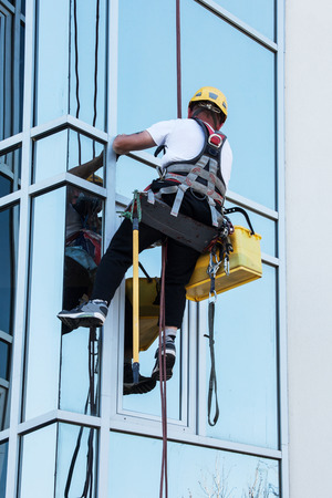 window washer working  at building outdoor hanging on ropeの写真素材