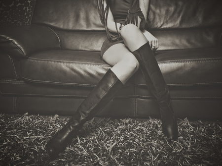 fashion girl in high heel leather  boots sit on leather sofa indoor shot retro bw lower bodyの写真素材