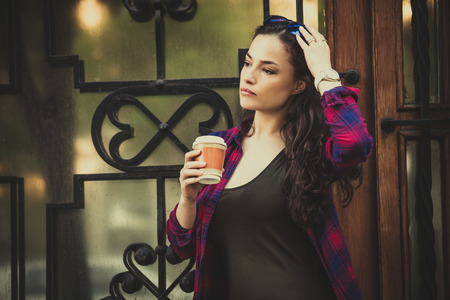 urban girl in city with smartphone and takeaway coffee in front of building entrance  summer dayの写真素材