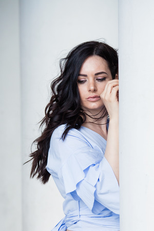 dark hair woman city portrait lean on column wind in hair closeupの写真素材