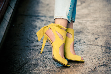 woman legs in leather yellow  high heel sandals and blue jeans outdoor in the city summer day closeupの写真素材