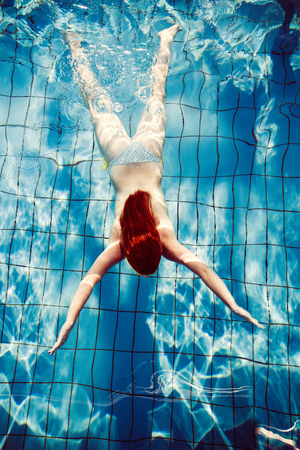 redhead girl in bikini dive in pool full body shot from above point of viewの写真素材