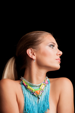 beauty young blonde woman portrait with large blue necklace with fringe profile studio shotの写真素材