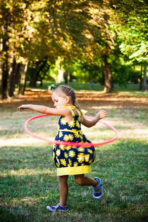 little girl play with hula hoop in park summer dayの写真素材