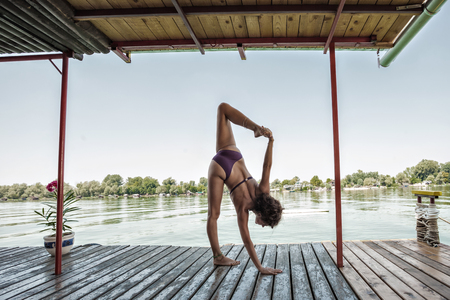 summertime yoga young woman doing yoga in bikini on wooden river raft hot summer dayの写真素材