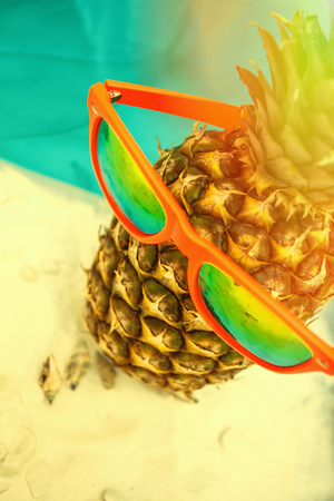 summer background pineapple with sunglasses on sandの写真素材