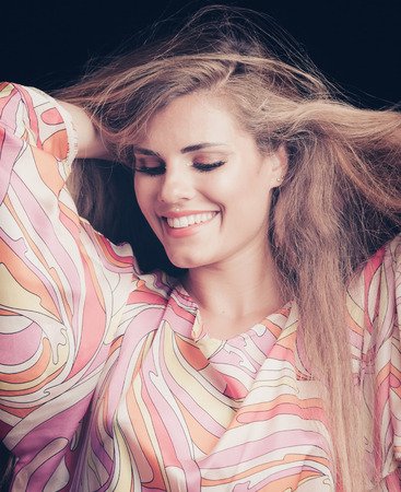 smiling beauty portrait of blonde girl with long hair in silky colorful dress studio shotの写真素材